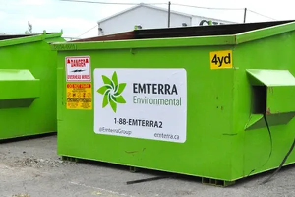 A mid green Emterra front-load bin with a black lid and a white panel carrying the Emterra pinwheel