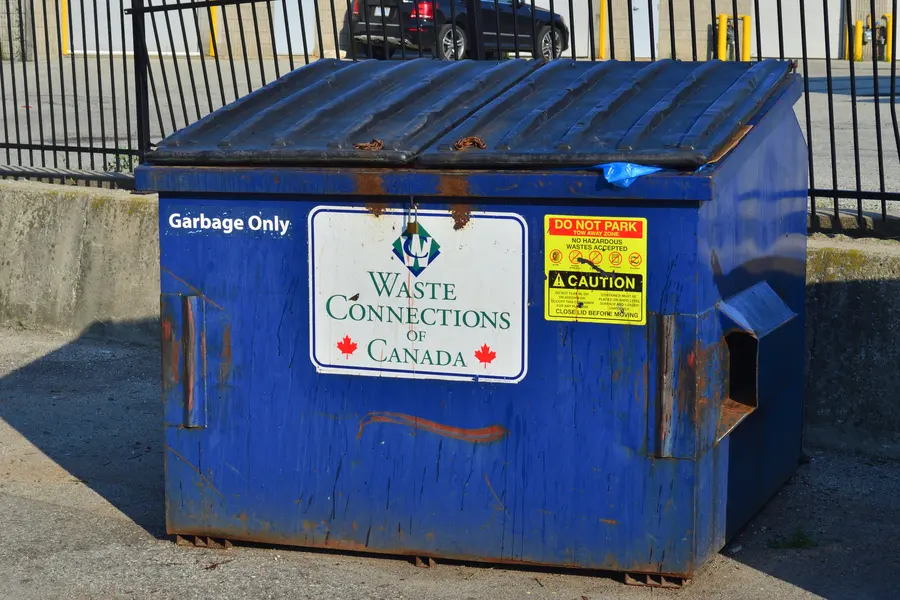 A royal blue Waste Connections of Canada front-load bin with a black lid